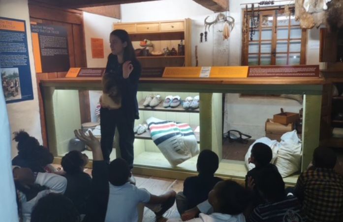  students sitting on the floor looking up at the presenter